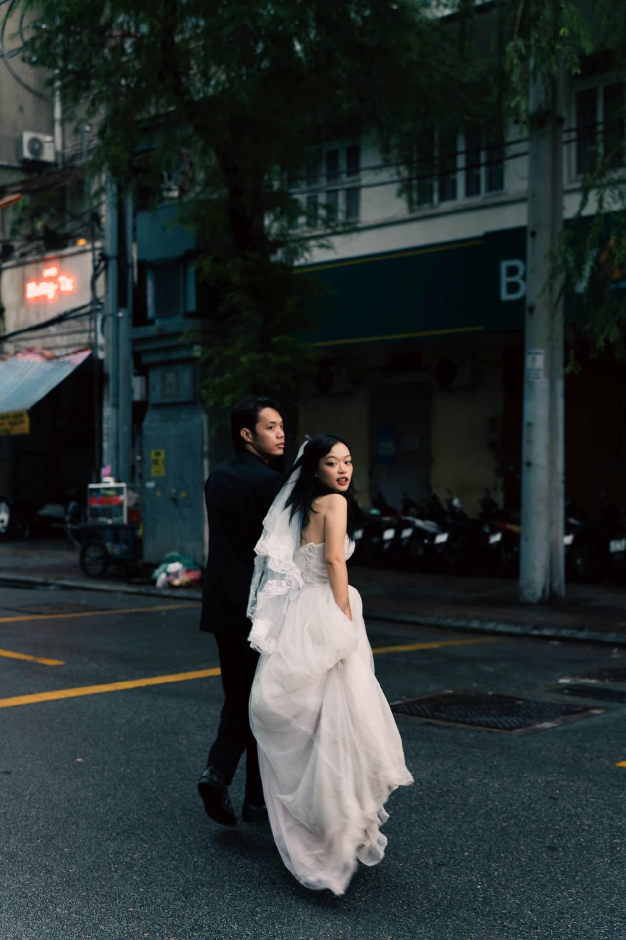 Two brides in elegant wedding gowns against a textured wall