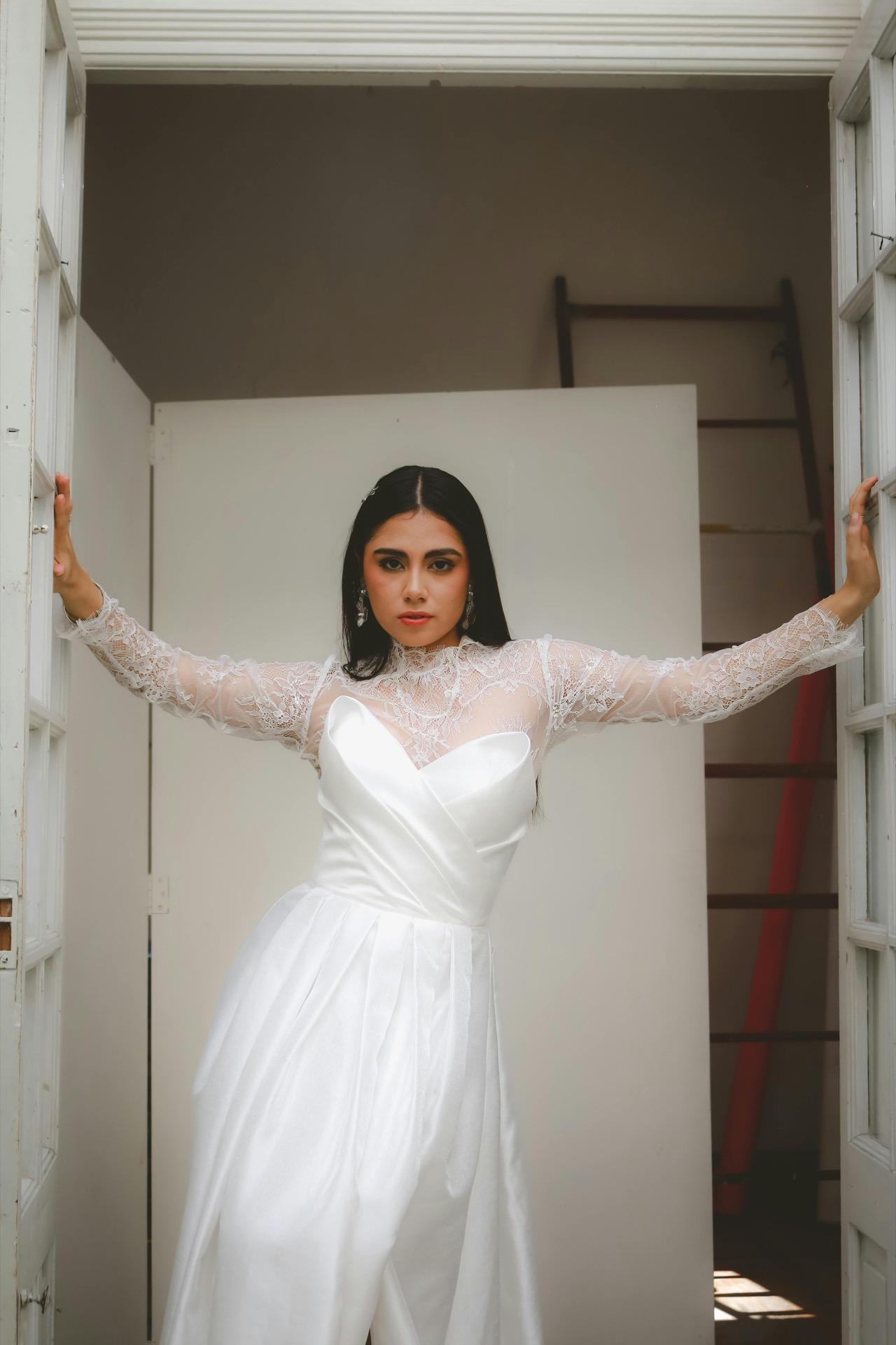 Bride in a lace long-sleeve gown posing in a doorway